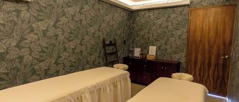 A room with two beds, a wooden wardrobe, a mirror, and a wall-mounted air conditioner.