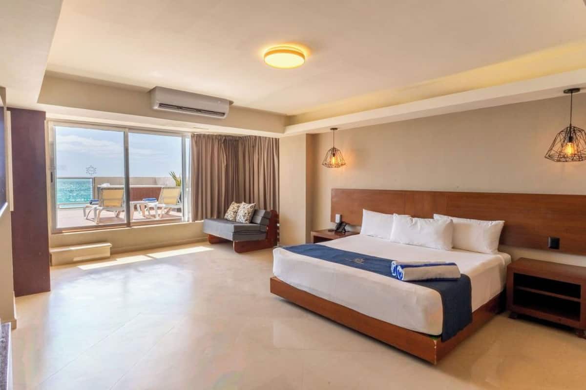 Ein Hotelzimmer mit einem großen Bett, einer Sitzecke mit Aussicht und einem Balkon.