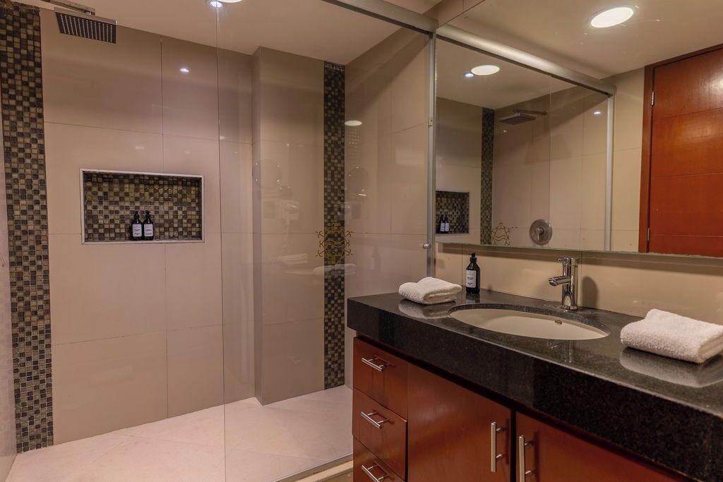 A modern bathroom with a large mirror, a sink, and a shower area.