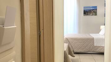 Une chambre d’hôtel comprenant un lit, une table de chevet, un climatiseur fixé au mur et une fenêtre avec des rideaux.