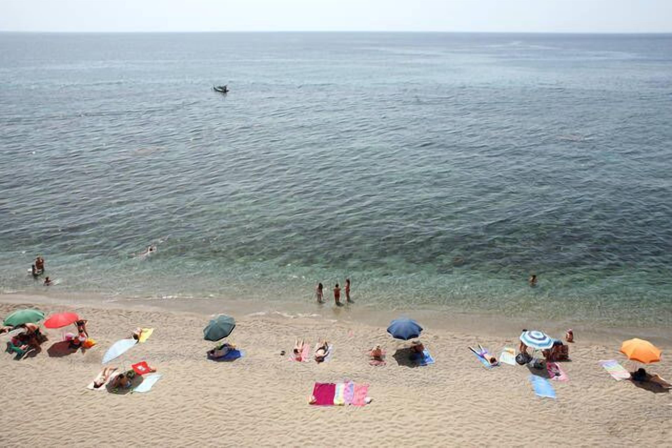 Une plage où des gens se prélassent au soleil et se baignent.