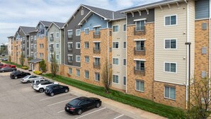 A multi-story apartment building with a parking lot in front. - WaterWalk Extended Stay by Wyndham Wichita (Wichita)
