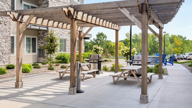 An outdoor patio area with wooden pergolas, picnic tables, and a barbecue grill. - WaterWalk Extended Stay by Wyndham Wichita (Wichita)