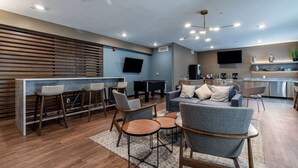 A modern living area with a bar, seating, a flat-screen TV, and a kitchenette. - WaterWalk Extended Stay by Wyndham Wichita (Wichita)