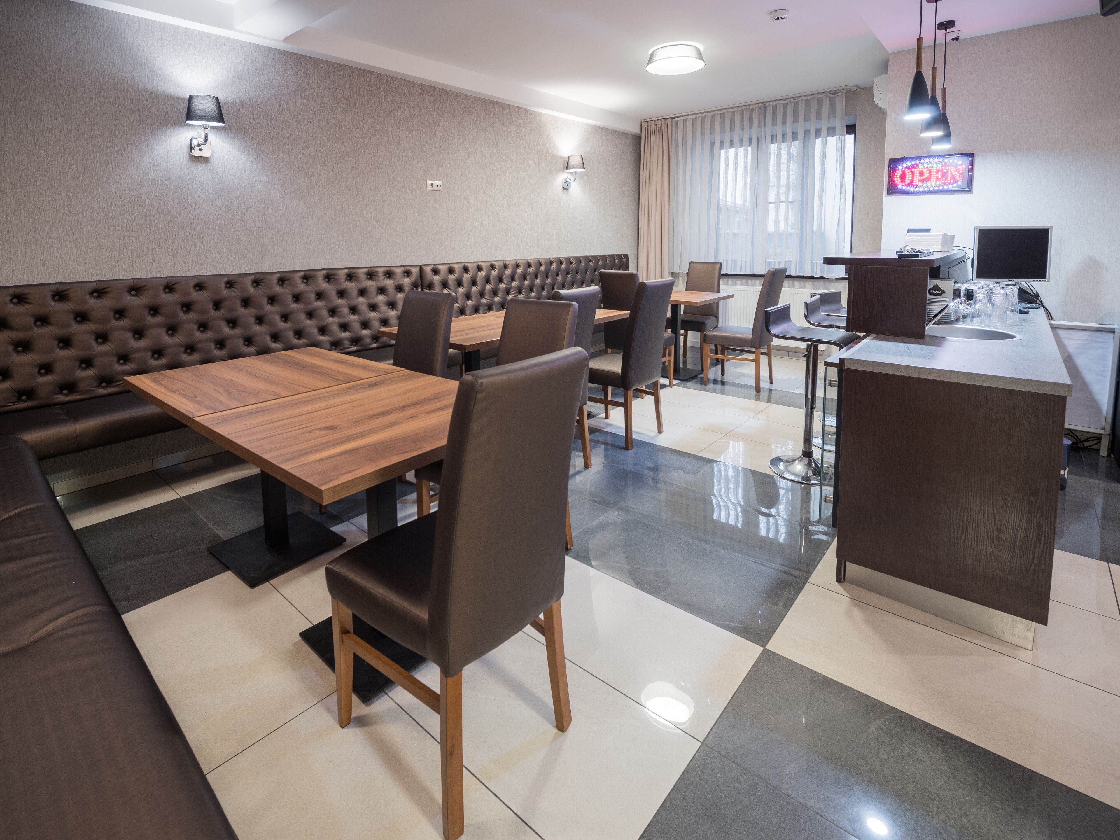 A modern restaurant with a mix of booth seating and tables, a bar area, and a visible 'OPEN' sign.