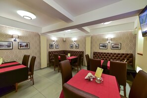 Um restaurante com cabines e mesas, algumas com toalhas vermelhas, e molduras de quadros fixadas na parede.