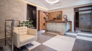 A modern lobby with a checkered floor, a sofa, a wooden cabinet, and a circular light fixture. - Hotel Miodowa (Kraków)