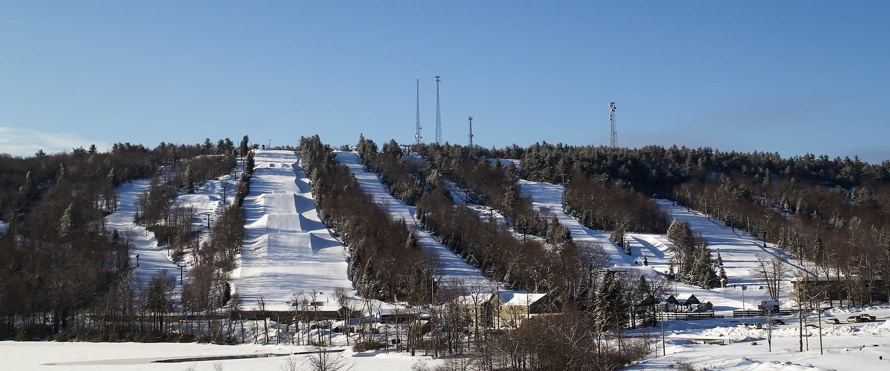 Une piste de ski enneigée, avec des arbres et des bâtiments en arrière-plan.