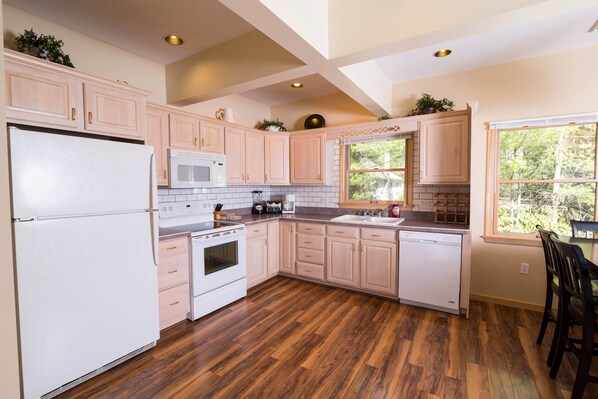 A kitchen with wooden cabinets, a refrigerator, a microwave, a stove, and a dishwasher. - Lake Harmony Inn (Lake Harmony)