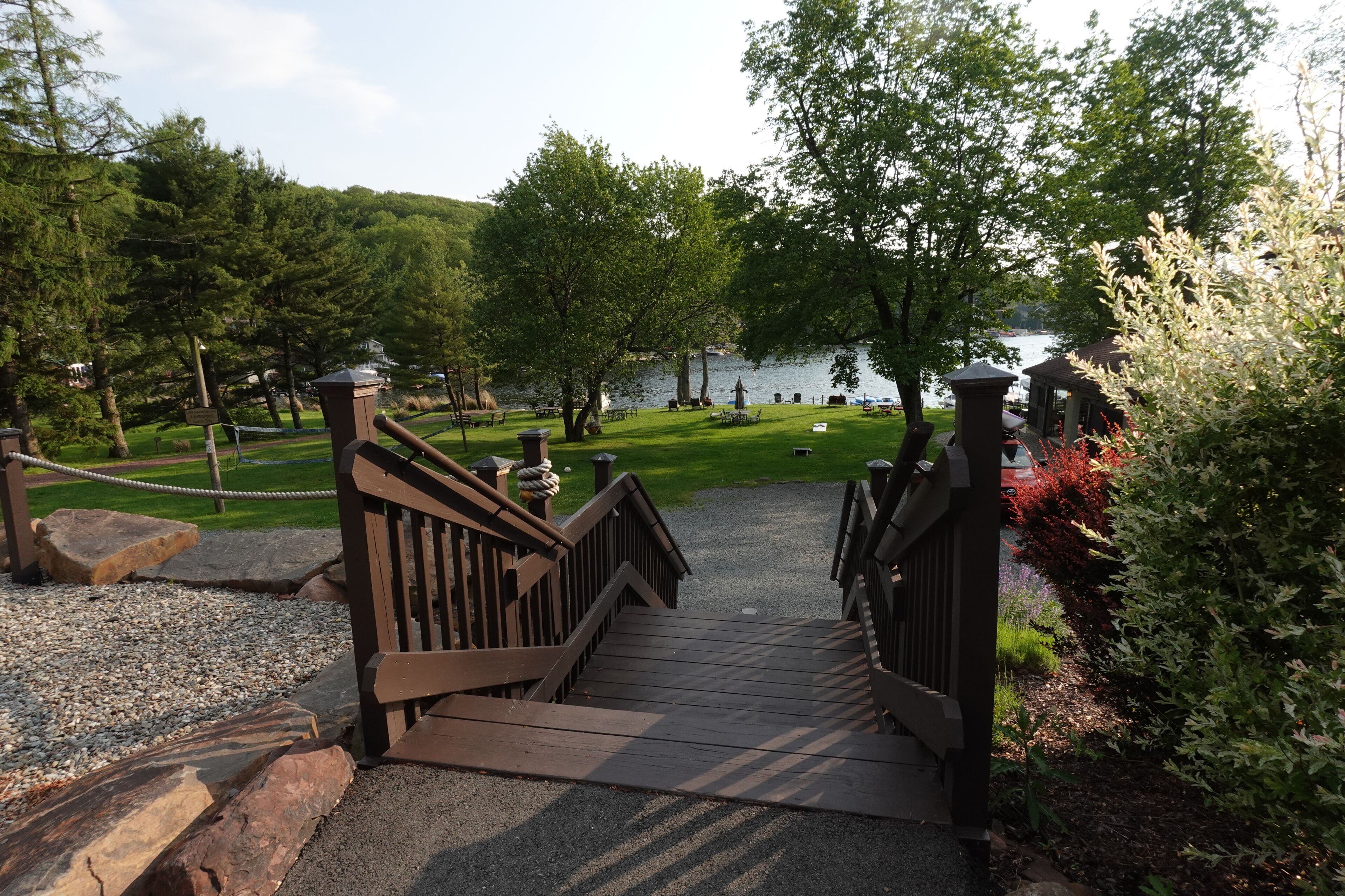 Una escalera de madera que lleva a un parque con mesas de picnic y vista al lago.