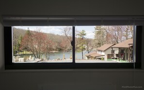 A view through a window of a lakeside property with a dock, boats, and houses. - Lake Harmony Inn (Lake Harmony)