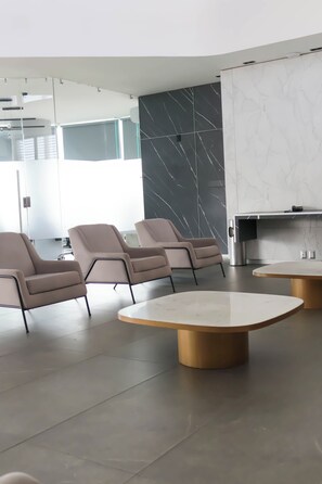 Contemporary hotel room with a seating area, kitchen, and minimalist design.