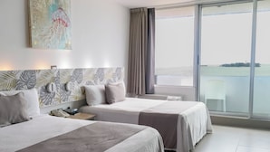 A hotel room with two beds, a large window with a view of the sea, and a painting on the wall.
