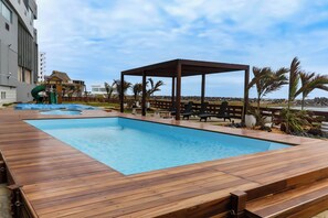 Relax by the serene pool surrounded by a wooden deck and shaded by a gazebo.