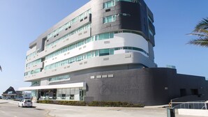 A modern hotel with a curved facade, multiple floors, and large windows.