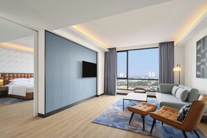 Una habitación de hotel con cama, televisión, sofá, mesa de centro y vistas a la ciudad.