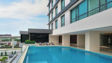 Et moderne hotel med swimmingpool i tagterrassen, store vinduer og udsigt over bybilledet.