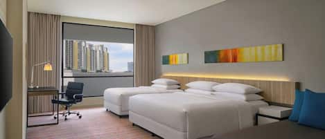 Habitación de hotel con dos camas, un escritorio, una silla y un televisor.
