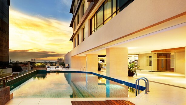 Un hotel moderno con piscina infinita en la azotea, amplias ventanas y vistas a la ciudad.