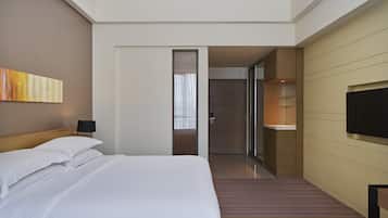 A hotel room with a large bed, a television, and a bathroom visible through an open door.