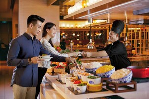 A buffet setup with various dishes and a chef serving food.