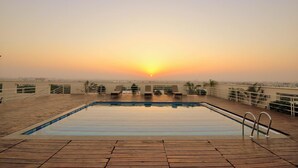 A rooftop pool with a sunset view, surrounded by lounge chairs and railings. - Hotel Marigold Jaipur (Jaipur)
