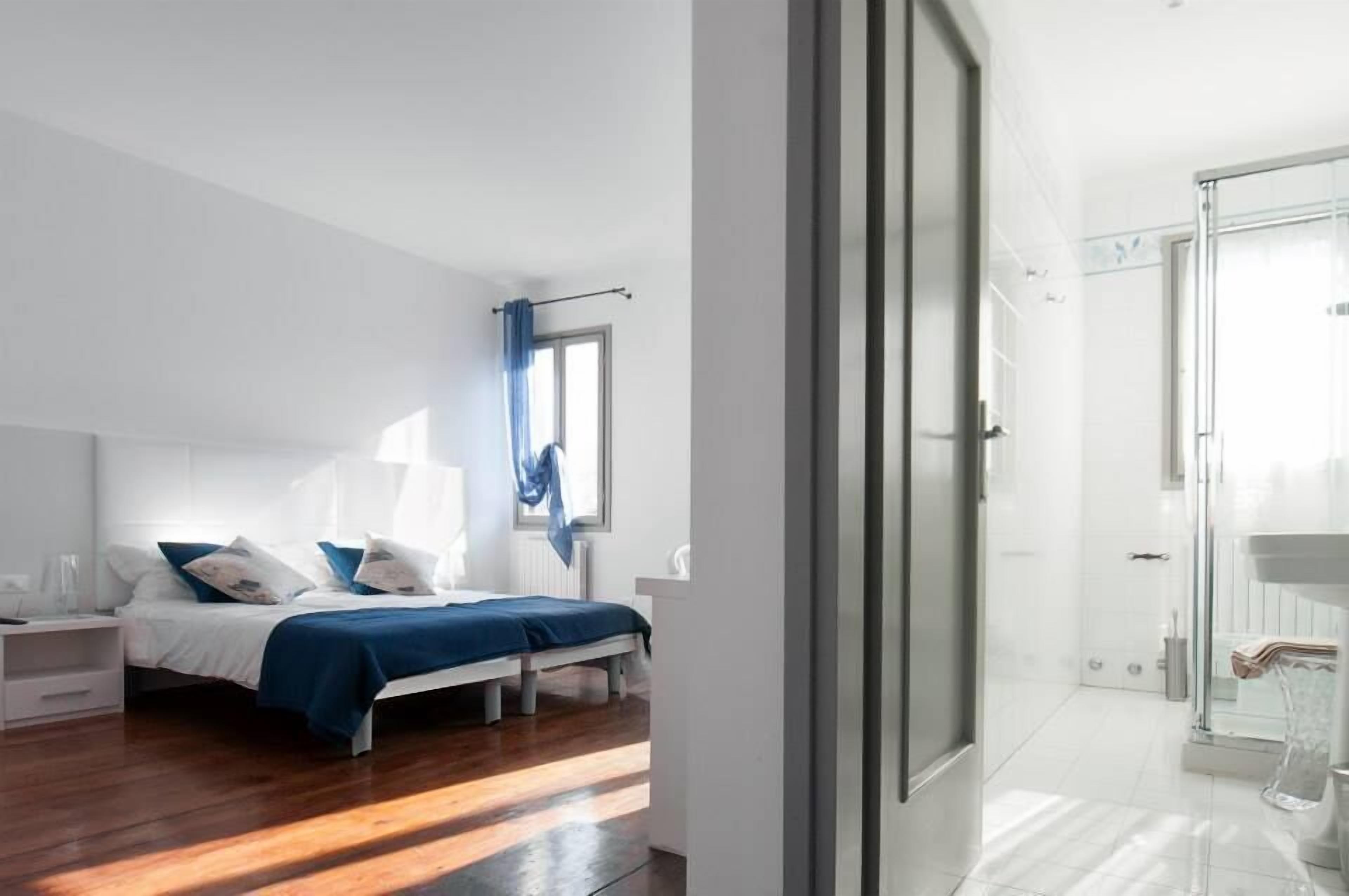 A modern bedroom with a bed, bedside table, and a window with curtains.