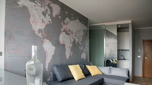 A modern living room with a grey sectional sofa, a world map on the wall, and a clear bottle on the table. - B&B Scrovegni (Padova)