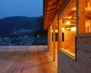 A wooden building with a balcony overlooking a cityscape at dusk. - Shin Kado Ya (Atami)