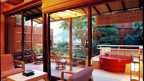 A modern interior with a view of a garden, a hot tub, and a dining area with chairs and a table. - Shin Kado Ya (Atami)
