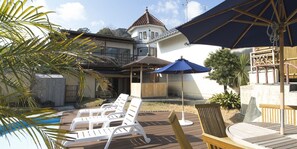 A backyard with a pool, lounge chairs, a wooden deck, and a house with a tiled roof. - Shin Kado Ya (Atami)