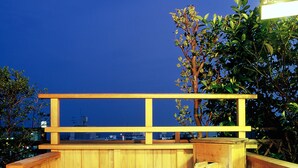 A hot spring bath area with wooden railings and a view of the sky. - Shin Kado Ya (Atami)