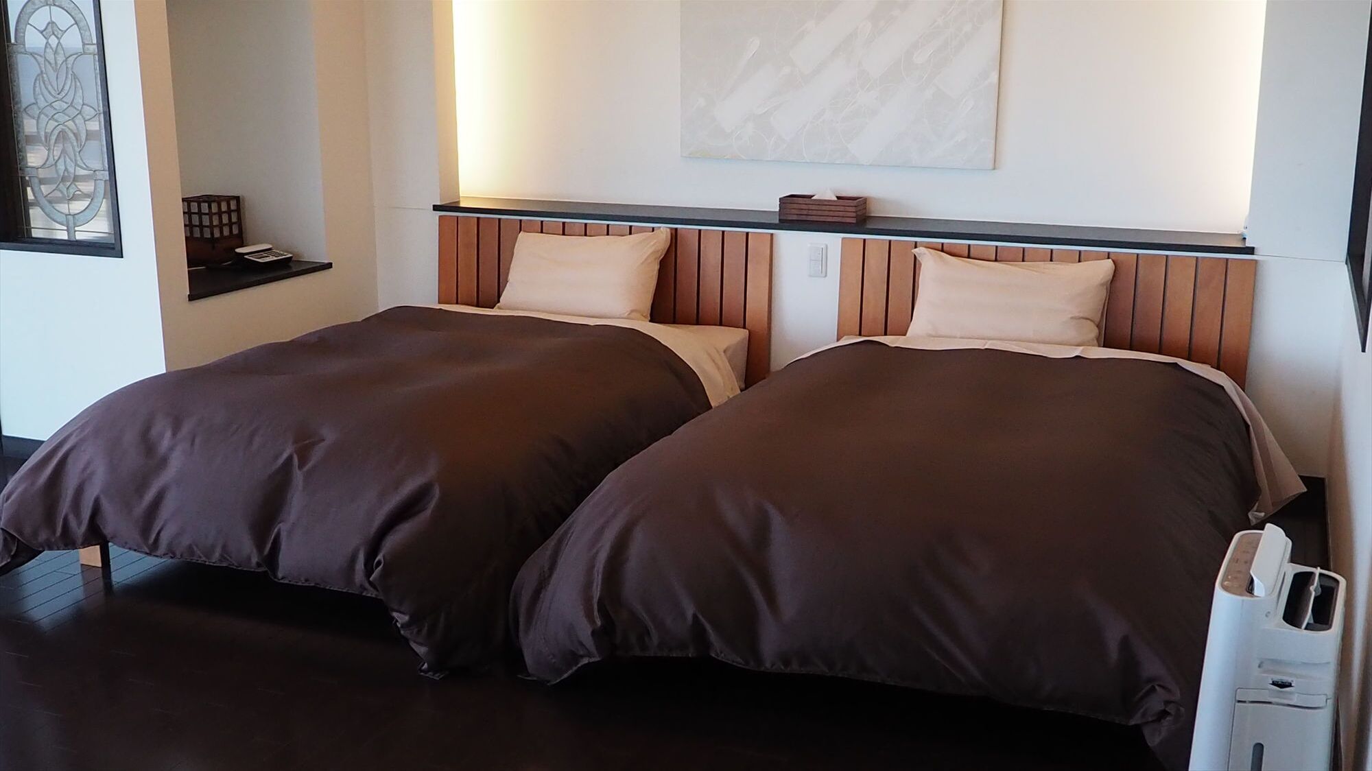 Cama doble con cabecera de madera, mesita de noche y una obra de arte colgada en la pared.