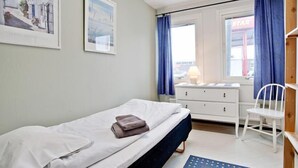 A bedroom with a bed, a dresser, a chair, and a window with curtains. - Bed's Rumsuthyrning (Norrköping)
