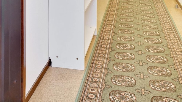 A hotel hallway with a carpeted floor, a white wall unit, and a lamp. - Bed's Rumsuthyrning (Norrköping)