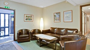 A lobby with a brown leather sofa, two armchairs, a coffee table, and framed artwork on the walls. - Bed's Rumsuthyrning (Norrköping)