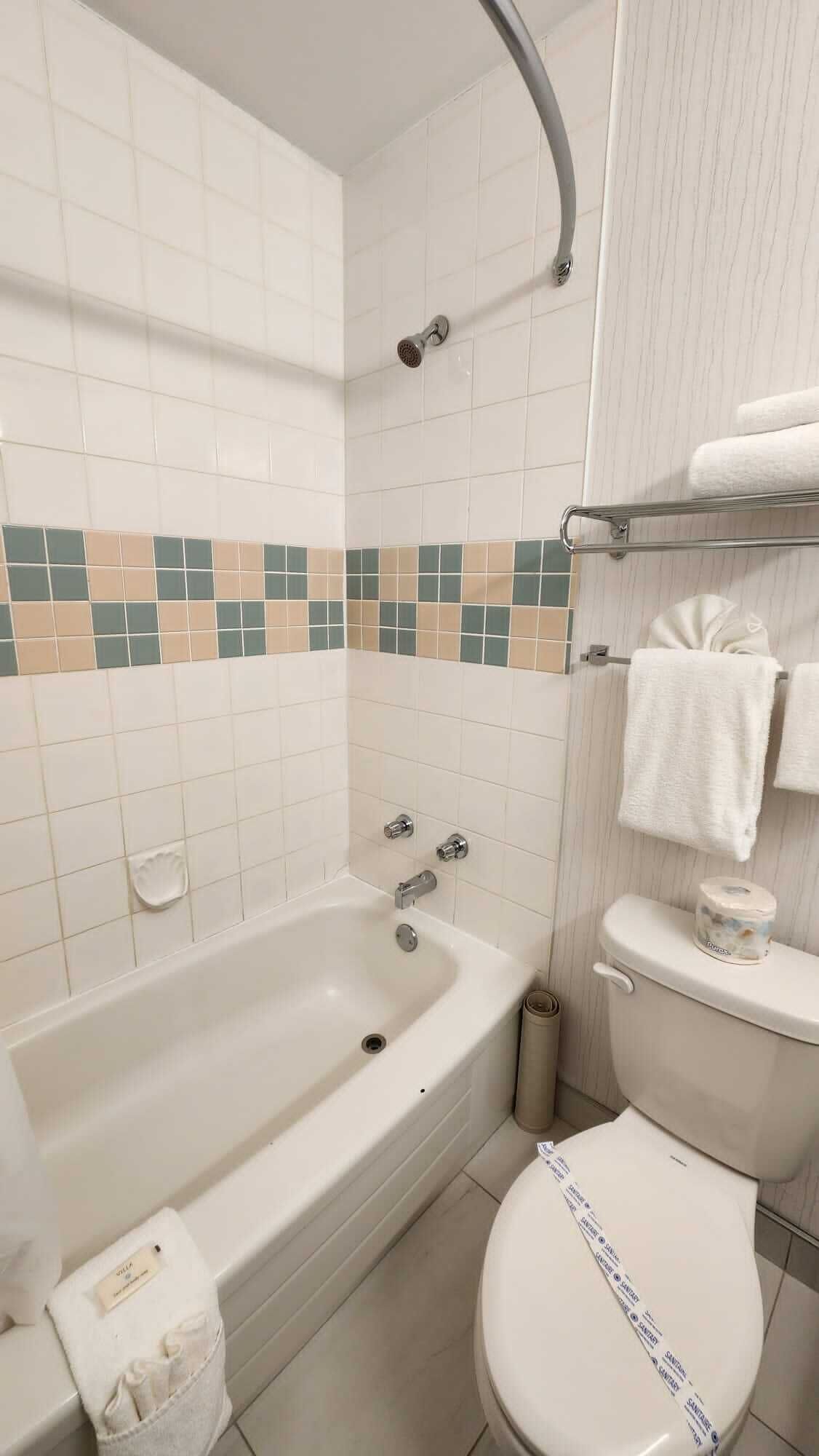 A bathroom with a bathtub, toilet, and a towel rack.