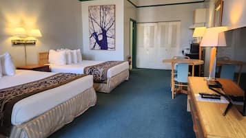 Hotelkamer met twee bedden, een eettafel met stoelen, een kleine televisie en een schilderij van een boom aan de muur.