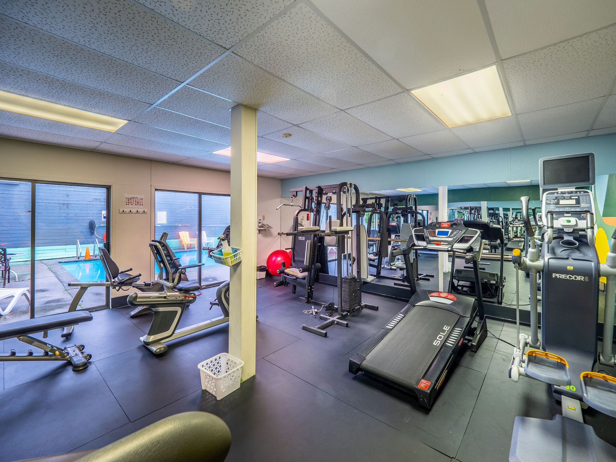 A gym with treadmills, weight machines, and a pool area.