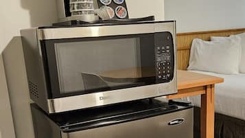 Una kitchenette compacta equipada con microondas, cafetera y refrigerador.