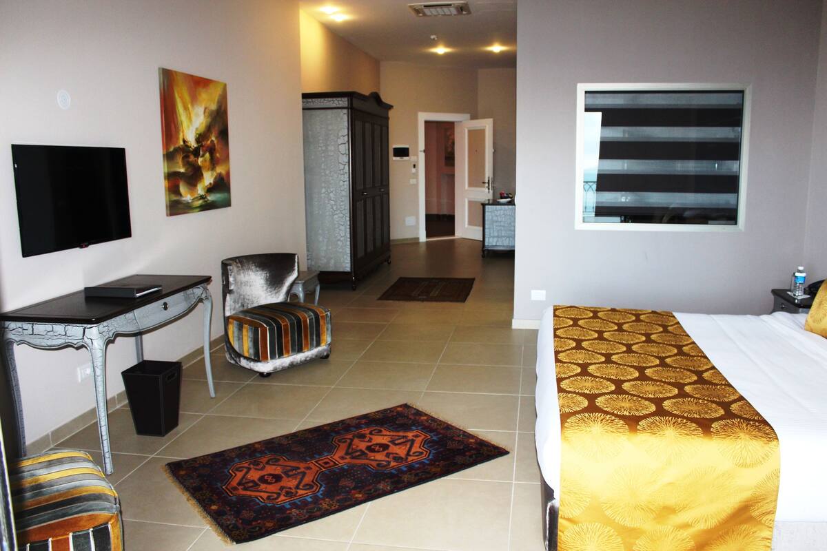Ein Hotelzimmer mit Bett, Schreibtisch, Fernseher, Schrank, Stuhl und Teppich.
