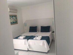 A double room with two beds, a bedside table, a wall-mounted air conditioner, and a framed picture. - Teos Hotel (Antalya)