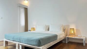 Un letto con una testiera bianca, una coperta blu e due abat-jour.