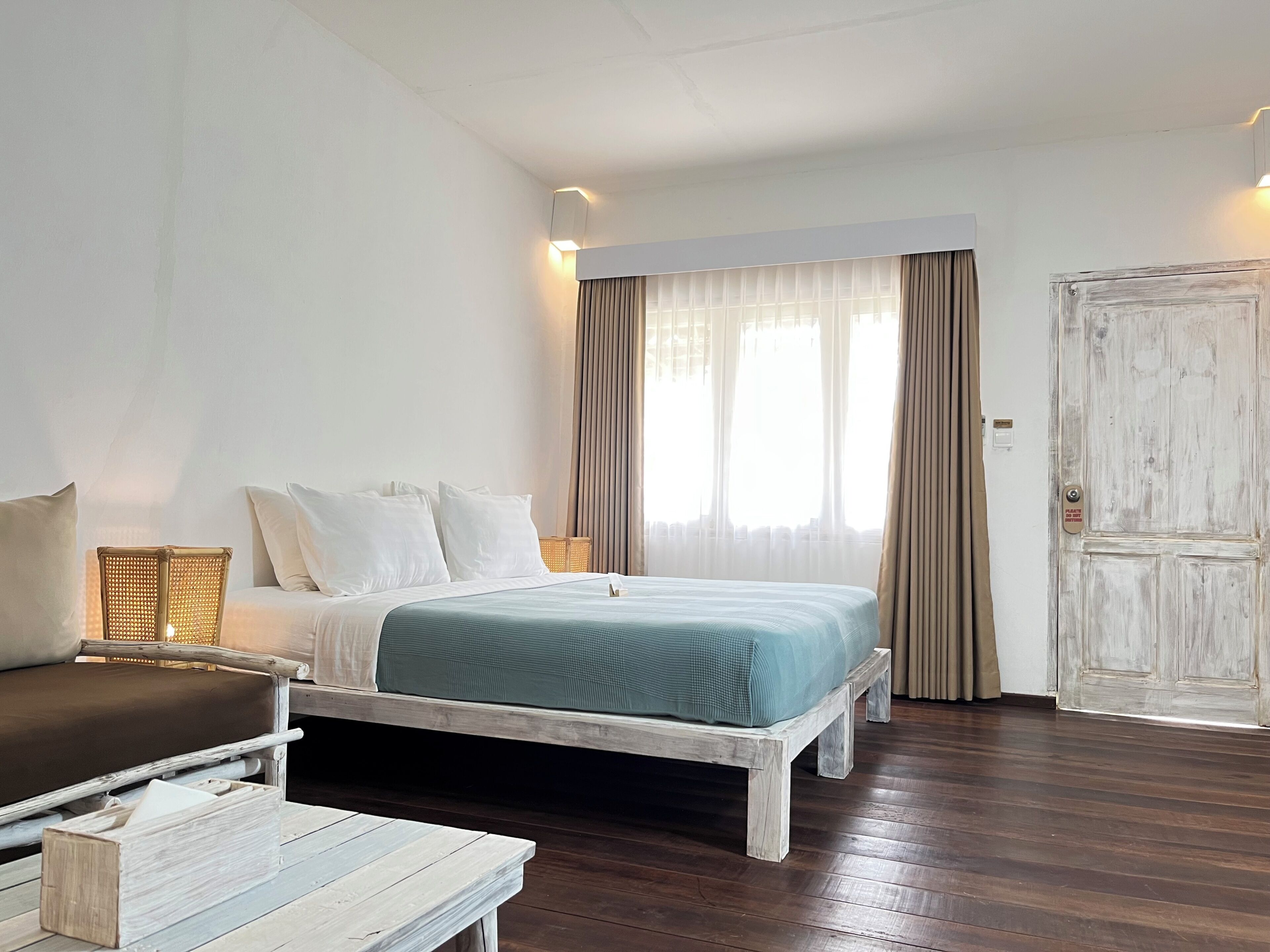 Un dormitorio con cama, mesitas de noche, una silla y una puerta.