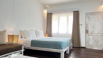 Un dormitorio con cama, mesitas de noche, una silla y una puerta.