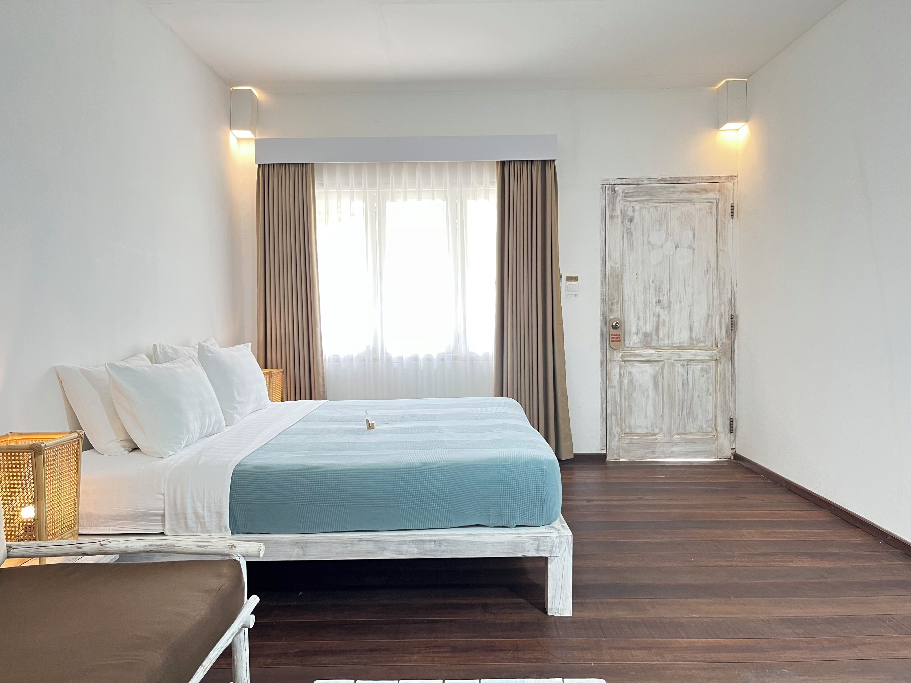 Un dormitorio con cama, mesita de noche, armario y ventana con cortinas.
