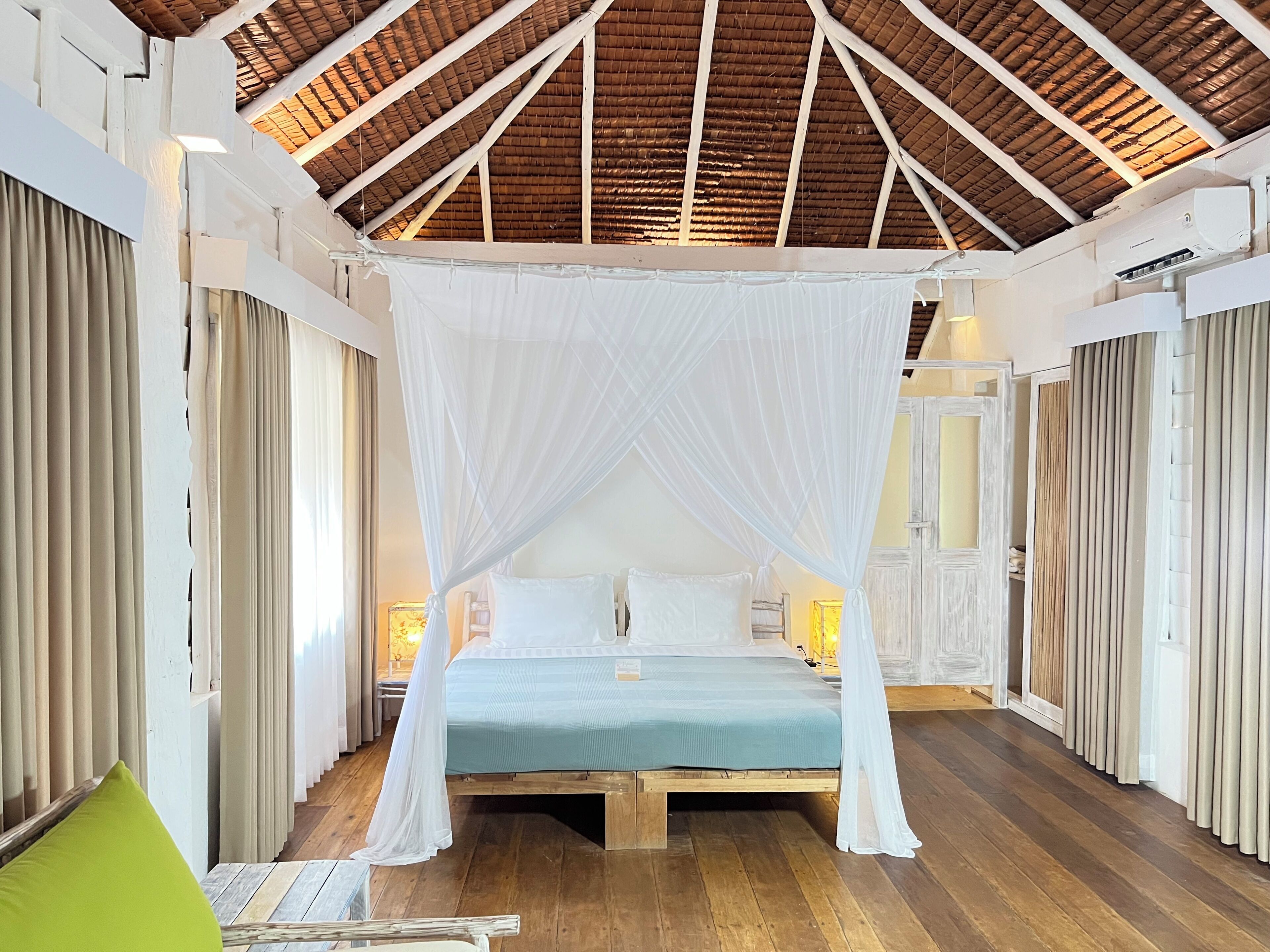 A room with a wooden ceiling, a bed with a canopy, and wooden flooring.