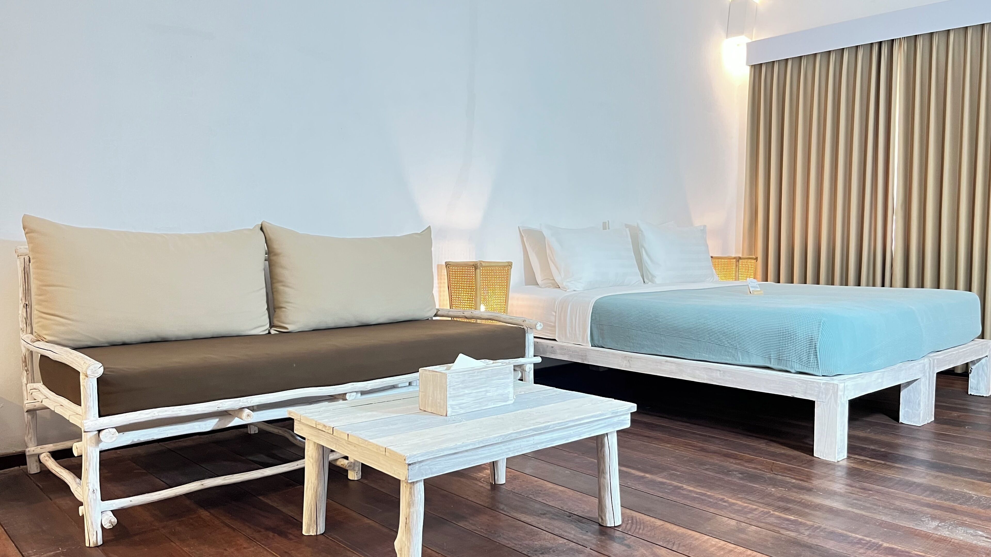A room with a sofa, a bed, a small table, and a lamp.