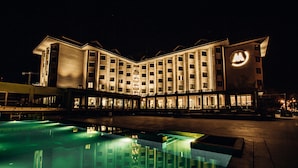 Un hotel con piscina, varios pisos y un logotipo destacado en la fachada.