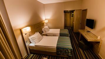 A hotel room with two beds, a TV, a desk, and a mirror.